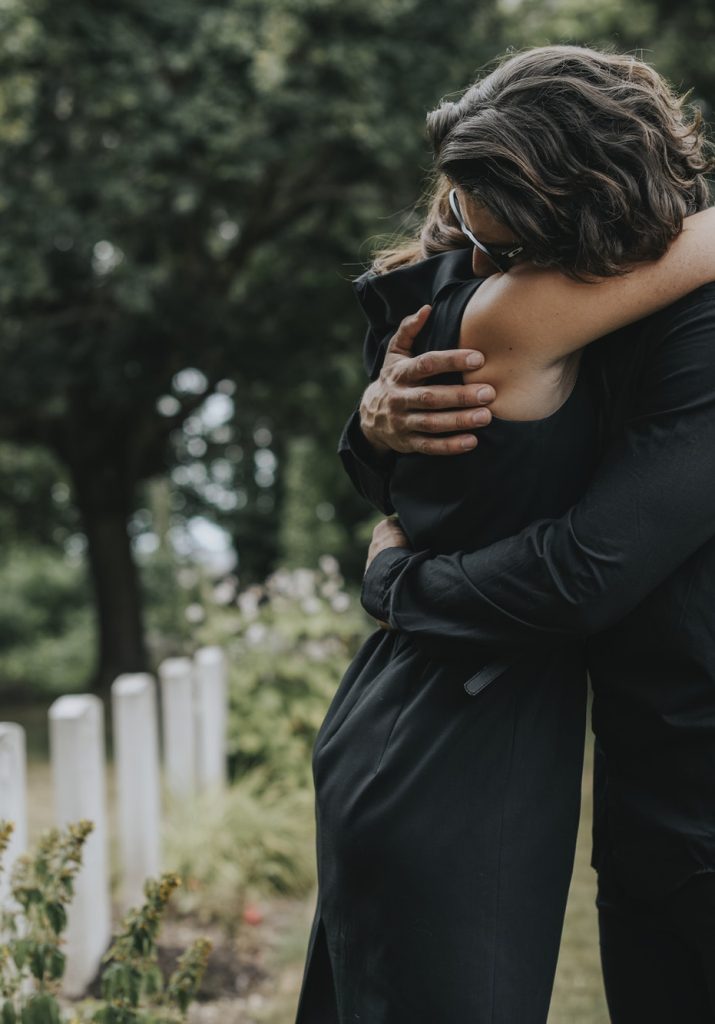 husband-trying-to-comfort-his-wife-at-a-graveyard.jpg